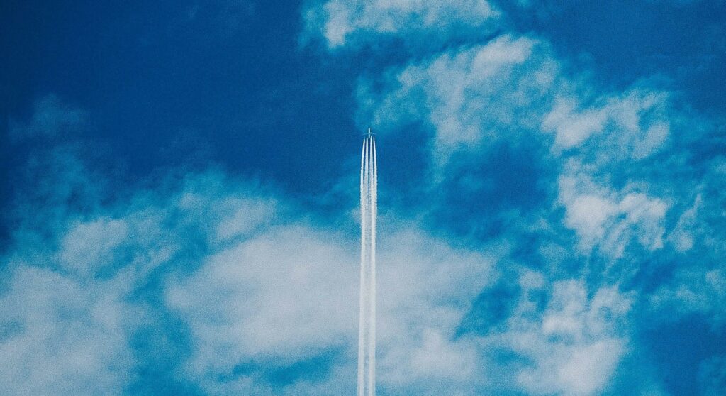 Plane soaring through blue sky and white clouds