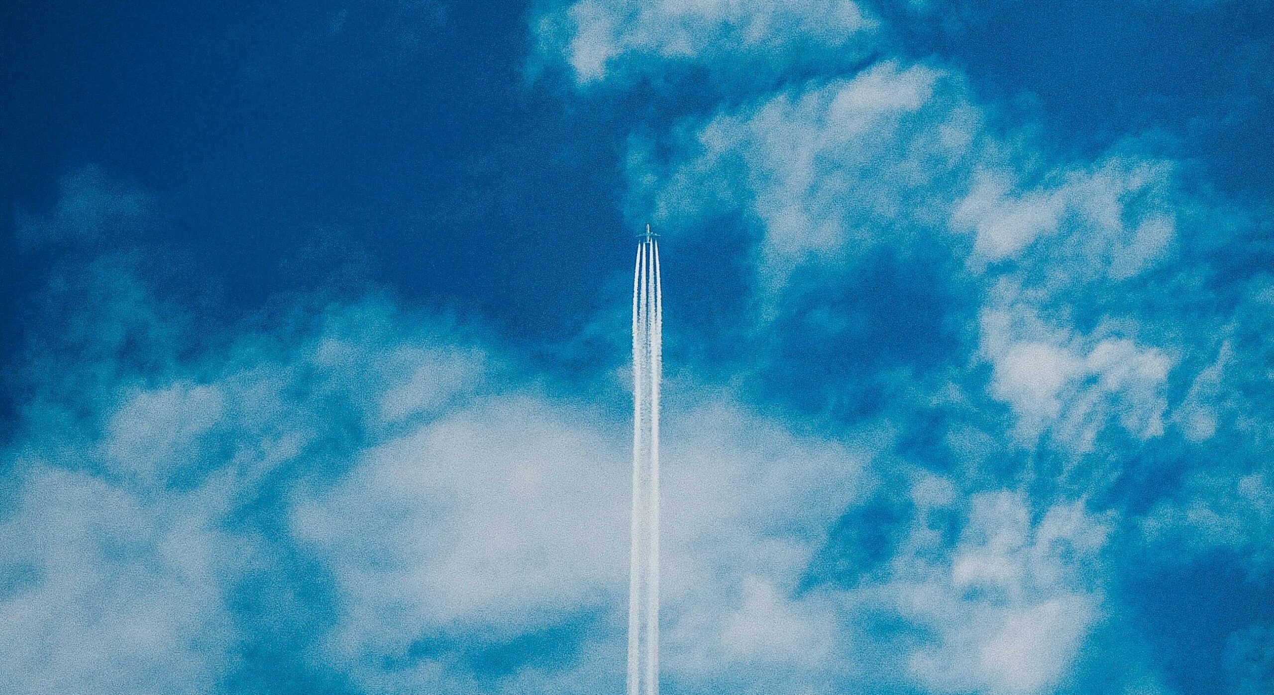 Plane soaring through blue sky and white clouds